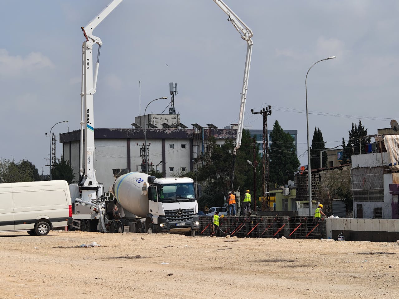Concrete mixer trucks and construction workers at an urban building site.